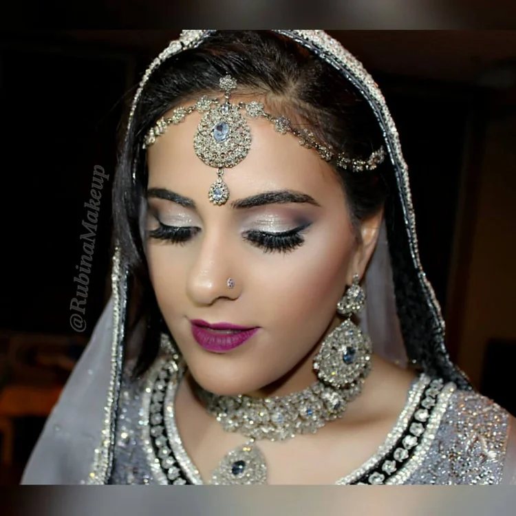 Bride in a silver dupatta and matha patti with soft smoky eyes and a berry lip